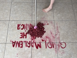 Dancing in my underpants. Tiled foor with words Quindi Marlena, домой не возвращайся written in red paint being errased with a mop